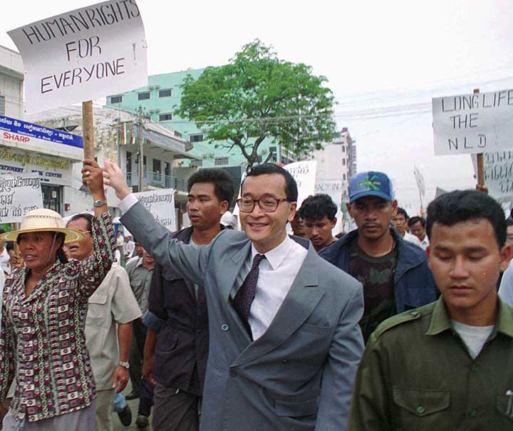 Sam Rainsy marches with protesters carrying signs that read, 'Human rights for everyone.'